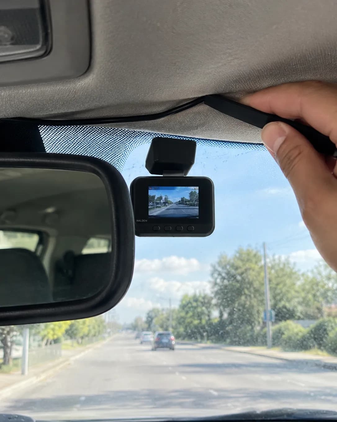 The trim tool tucking the thin cable into the edge of the headliner